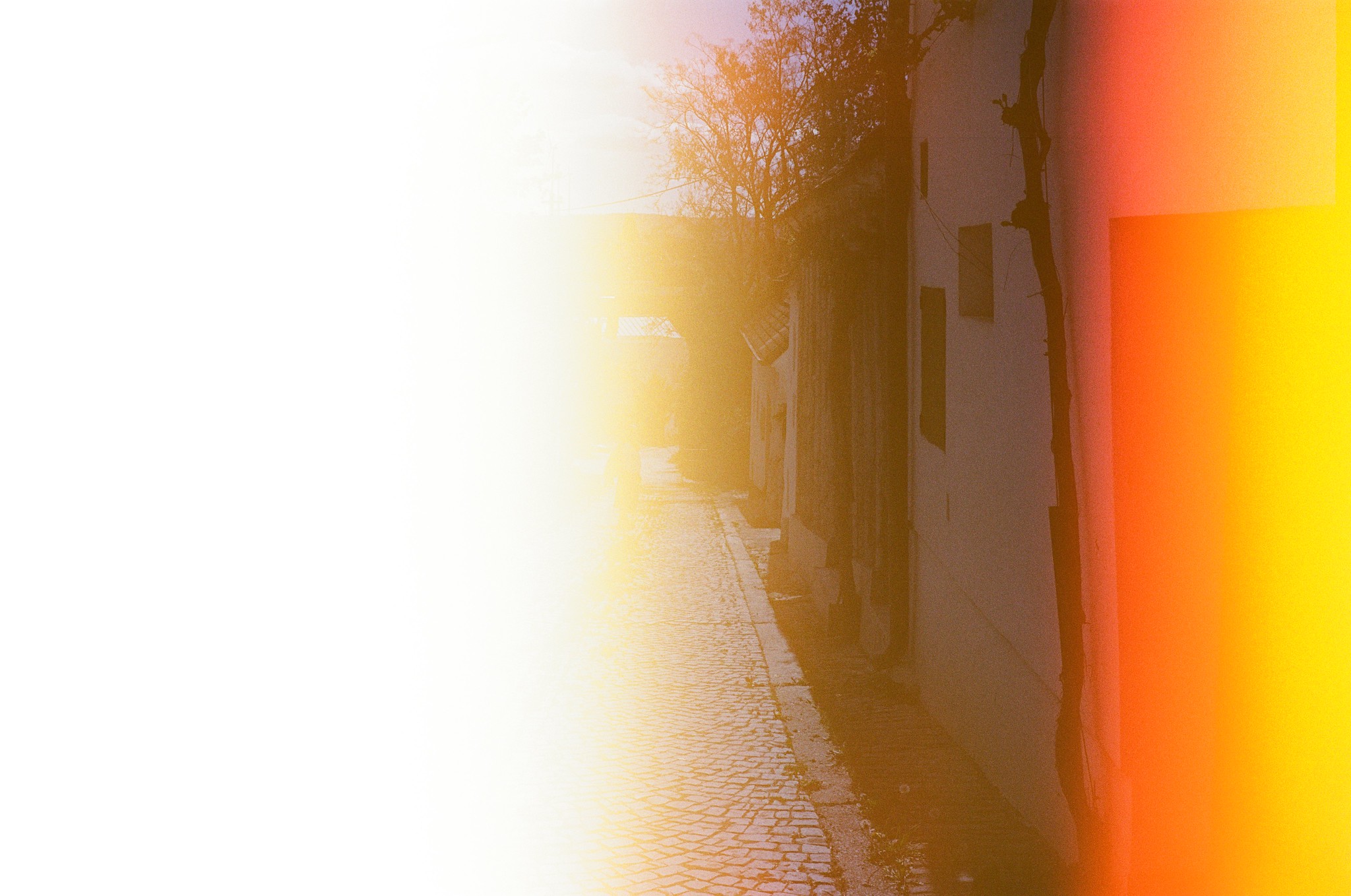 Lightleak auf einem Filmframe. Am Bild wäre eine Kellergasse von Poysdorf, die man zur Hälfte noch erkennen kann. Der Rest des Bildes ist in Überbelichtung eingetaucht.