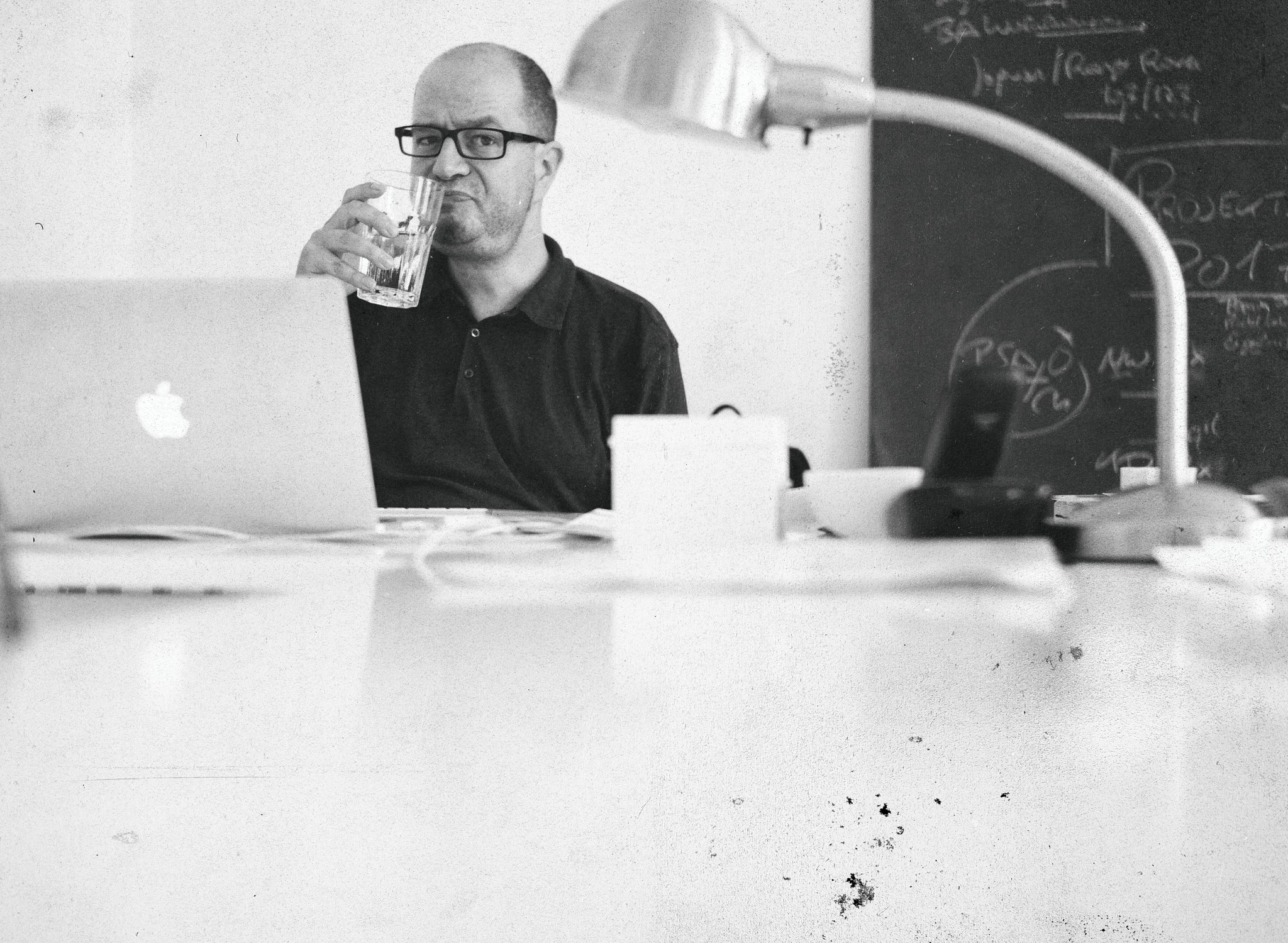 Karl sitzt am Schreibtisch im Büro und trinkt kaltes, klares Wasser